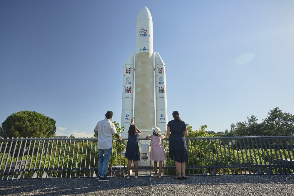 trois personnes regardant la fusée ariane 5
